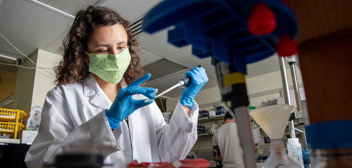 女学生戴着口罩在实验室里进行科学实验